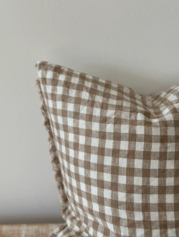 Brown and white checkered pillow on a neutral background