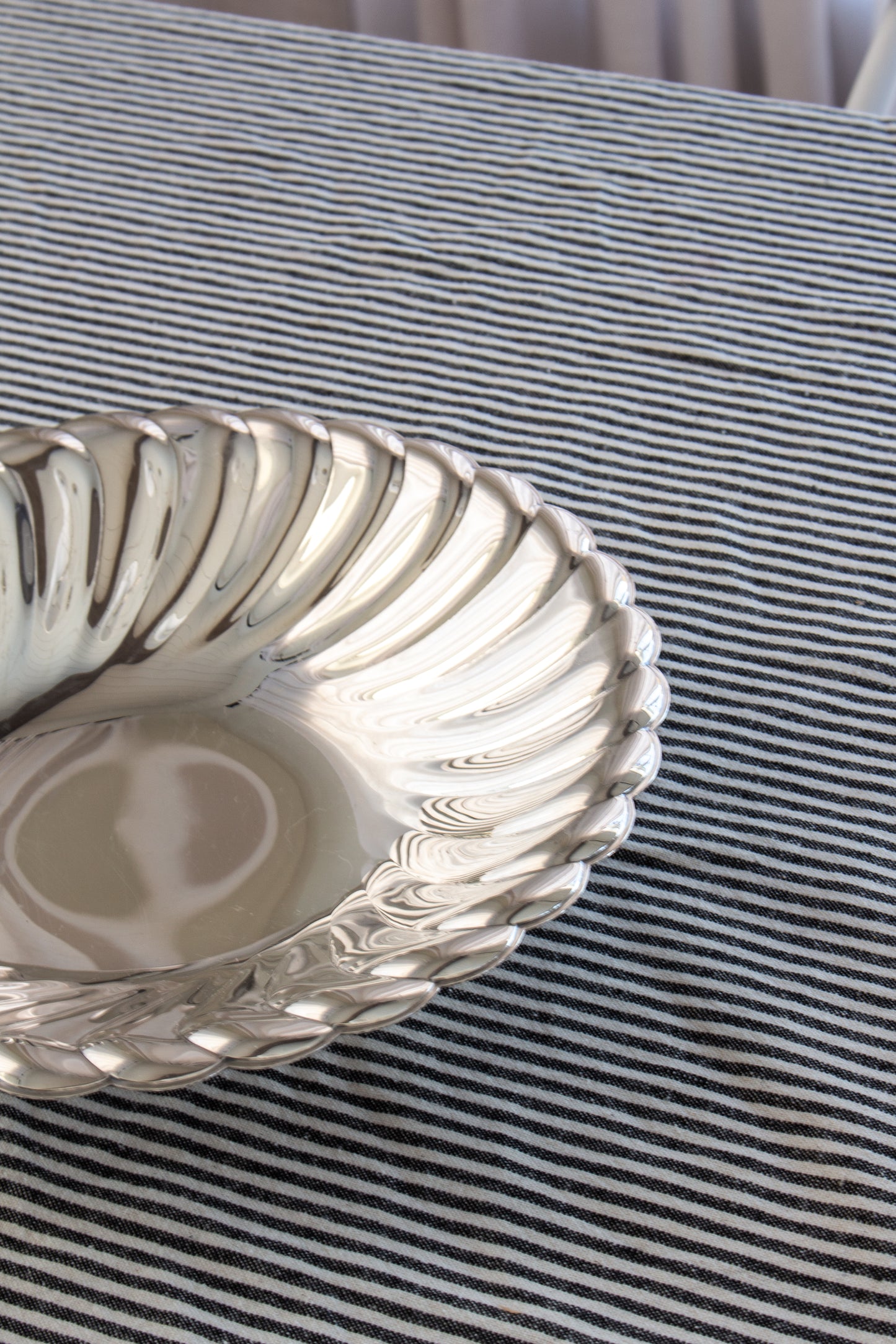 Silver bowl on a striped fabric surface