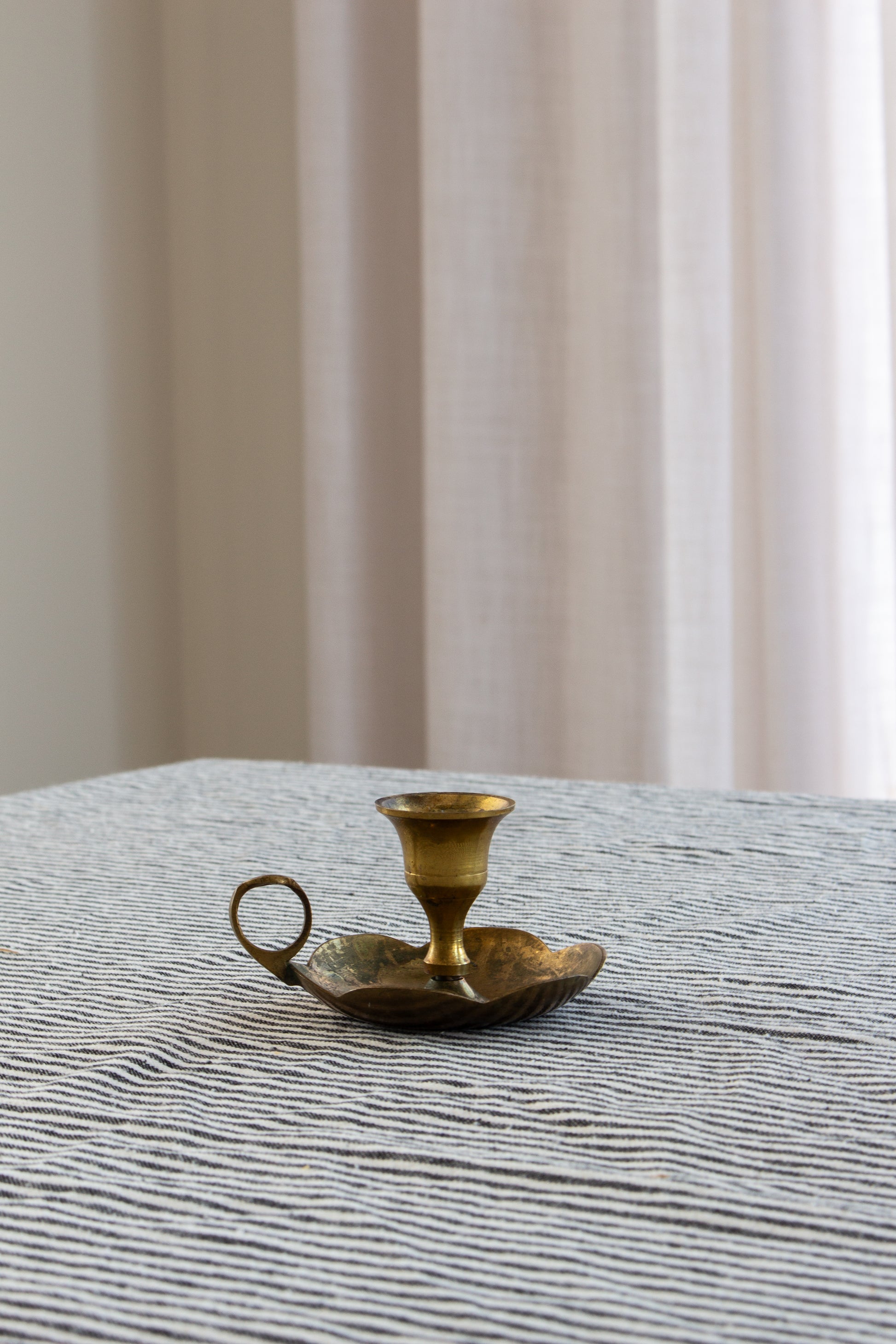 Brass candle holder on a textured surface with a neutral background