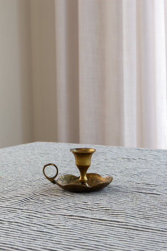Brass candle holder on a textured surface with a neutral background