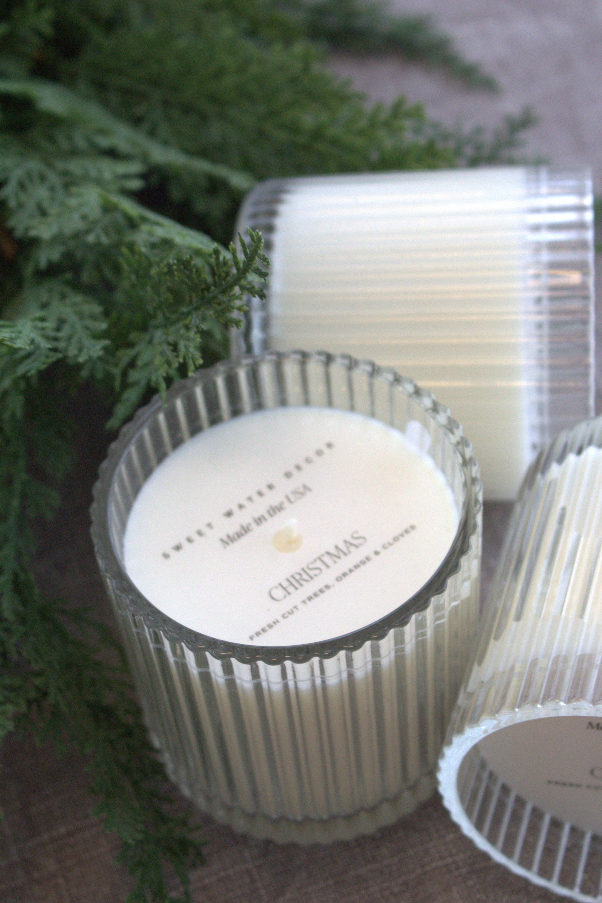 Three candles with labels in front of a green leafy background