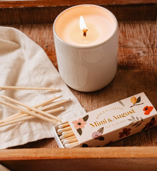 Candle with matches and packaging on a wooden surface