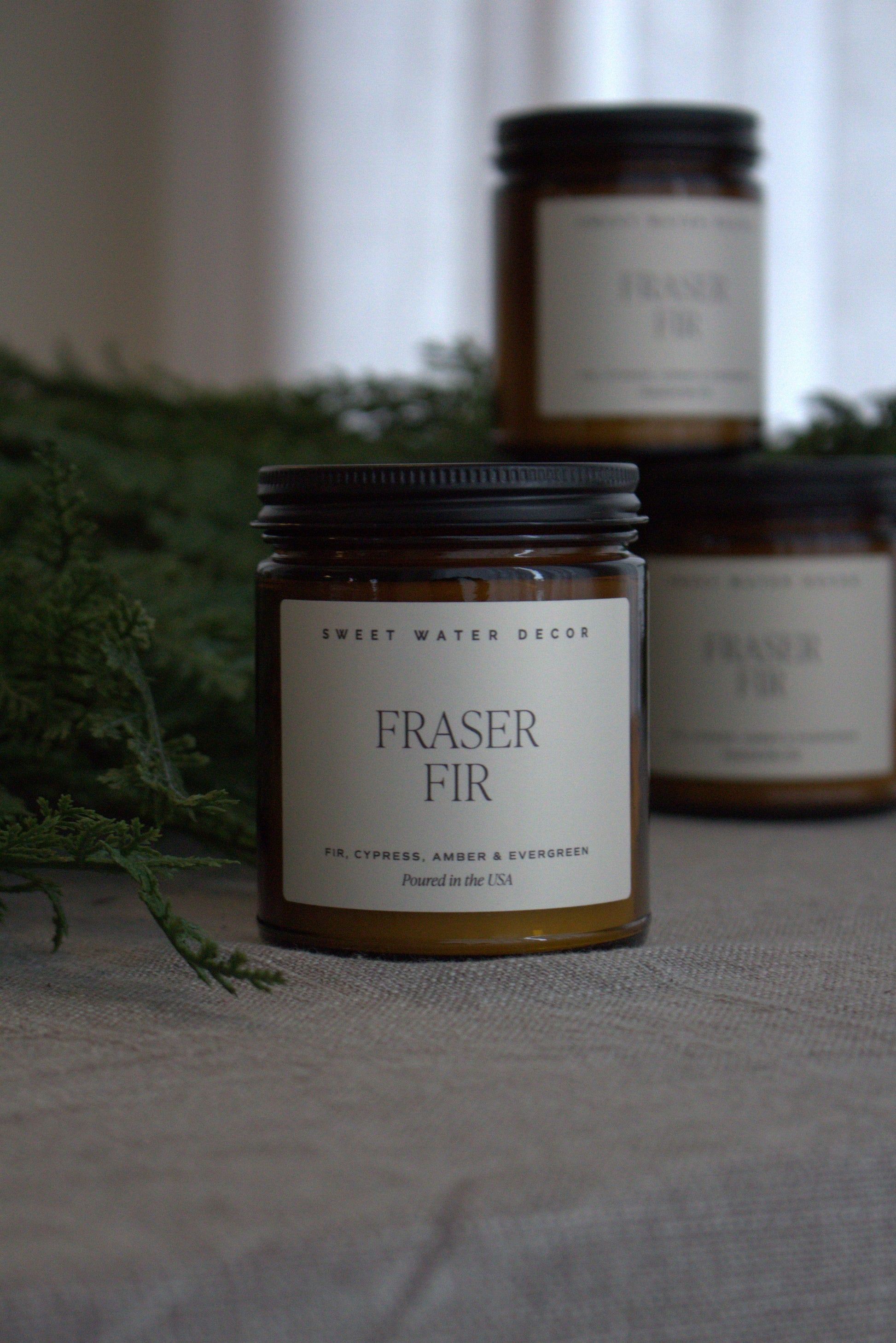 Two Fraser Fir candles on a neutral background