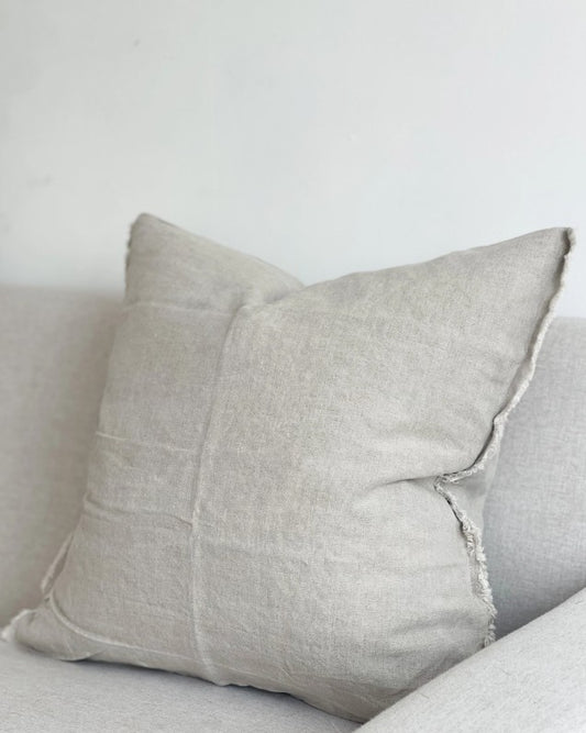 Gray pillow on a light gray sofa against a white wall
