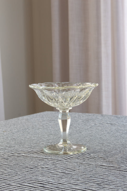 Clear glass compote on a textured surface with a neutral background