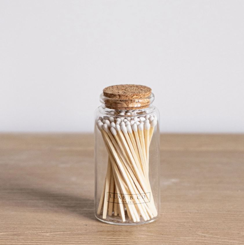 Glass jar with cork lid filled with matches on a wooden surface