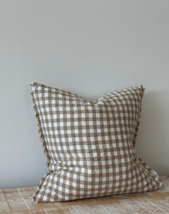 Checkered pillow on a wooden surface with a neutral background