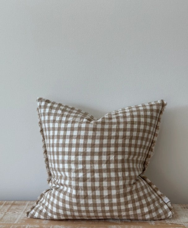 Checkered pillow on a wooden surface with a neutral background