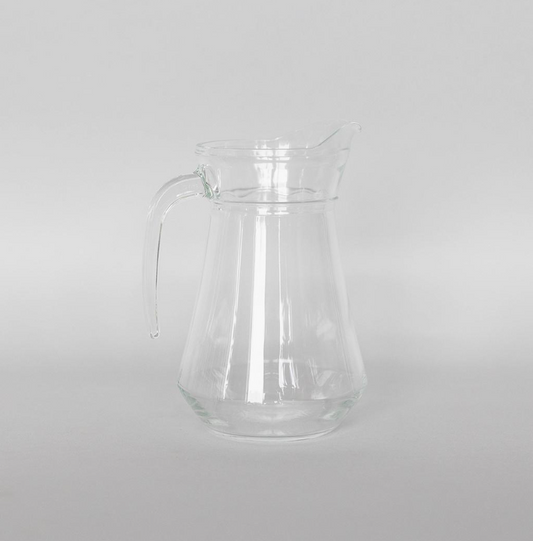 Clear glass pitcher on a light gray background