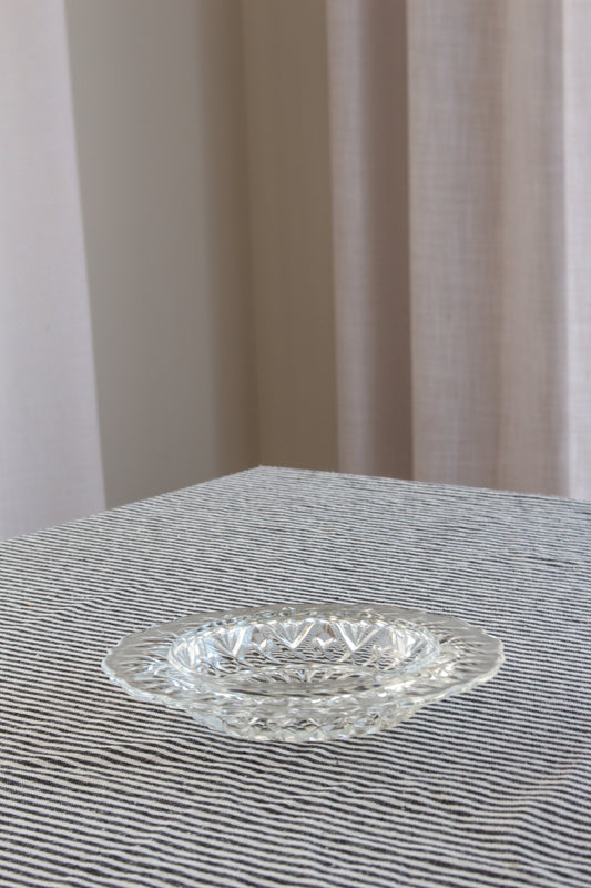 Clear glass plate on a striped fabric surface with a neutral curtain background