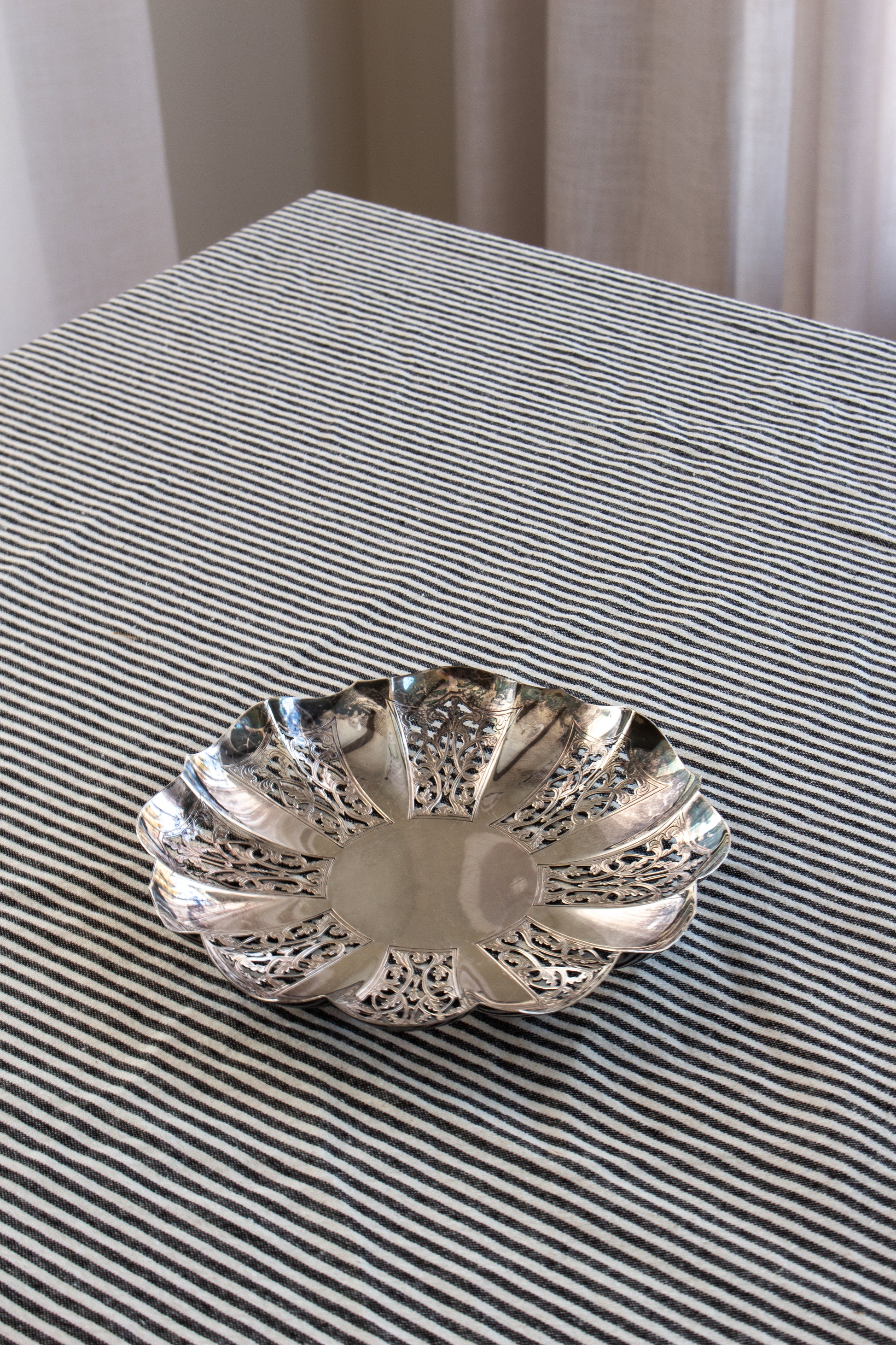 Silver decorative bowl on a striped fabric surface