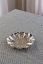 Silver decorative bowl on a striped fabric surface