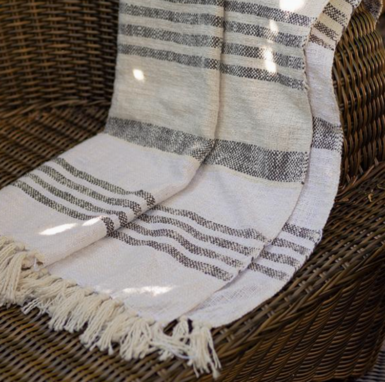 Striped blanket with fringes draped over a wicker chair