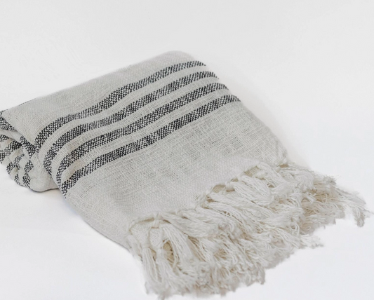 Textured blanket with black stripes and frayed edges on a light gray background