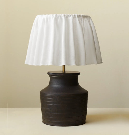 Table lamp with a white shade and dark brown base on a beige background